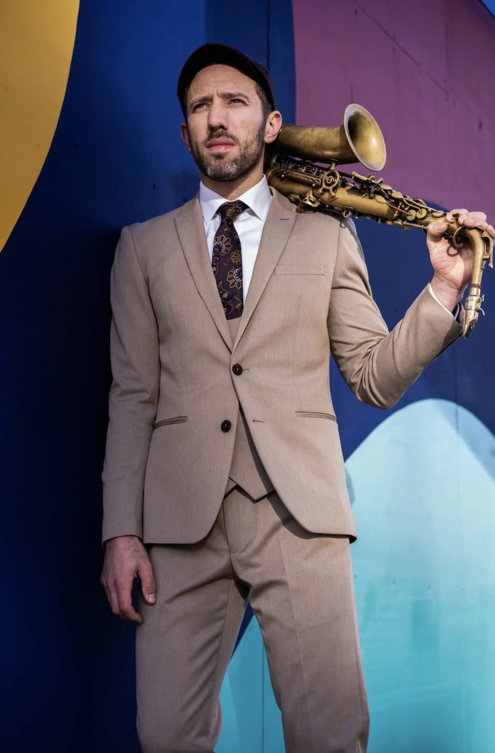 A performer photographed with his instrument against a mural.