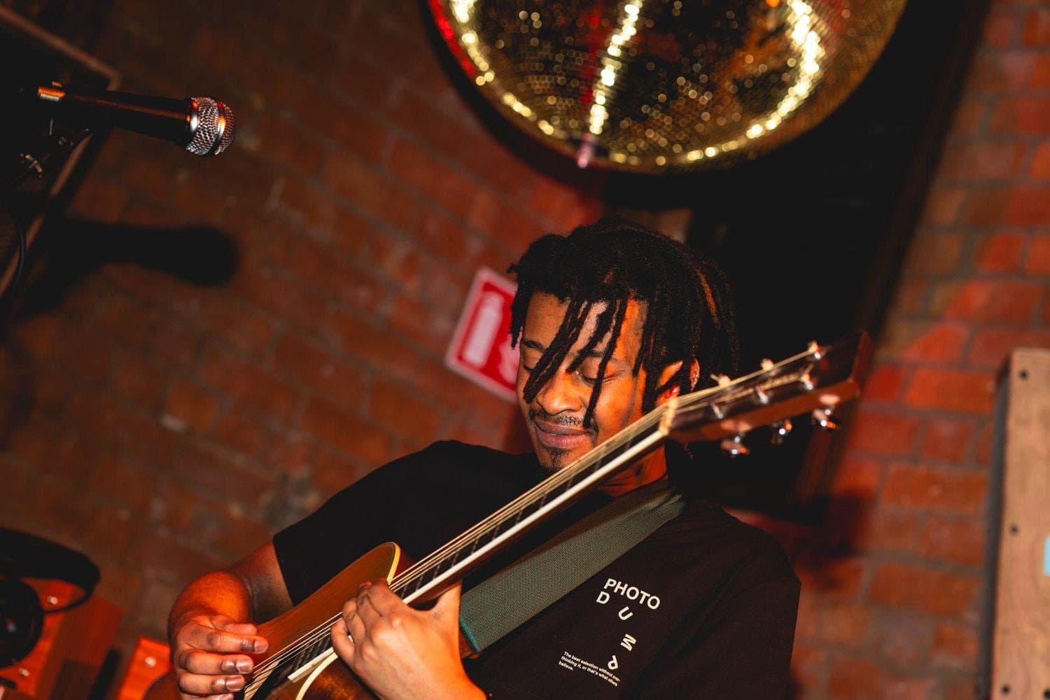 A bass player under a mirrorball, close to the crowd.