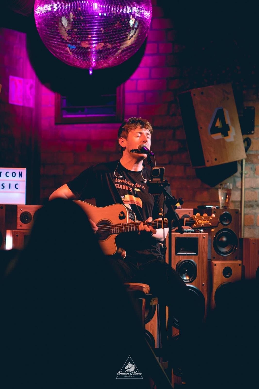 A solo musician singing and playing acoustic guitar.